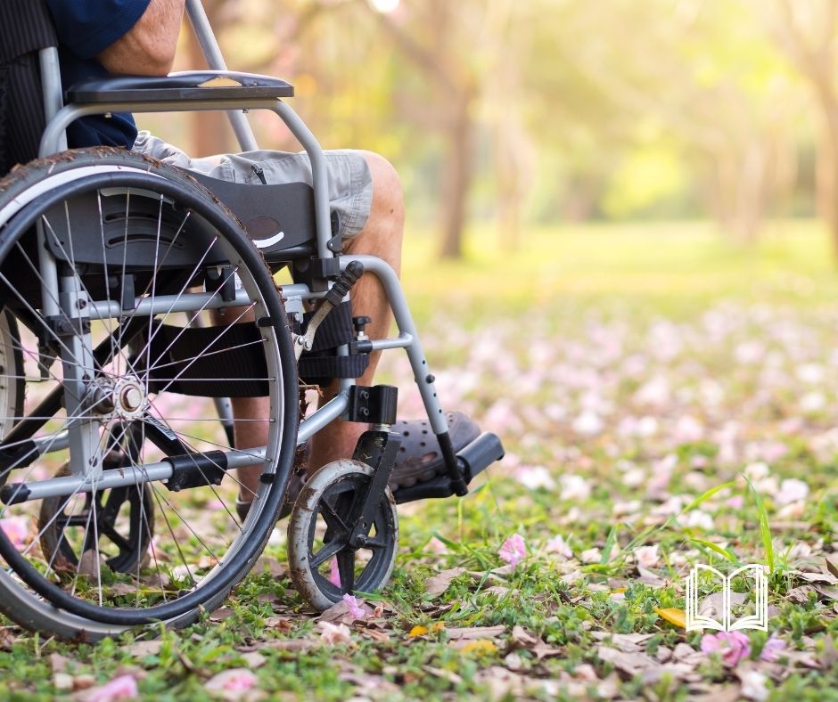 Side profile of a person in a wheelchair in a field with fallen leaves.