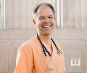 Prof. Dr. Jan Bonhoeffer smiling wearing orange scrubs and a stethoscope.