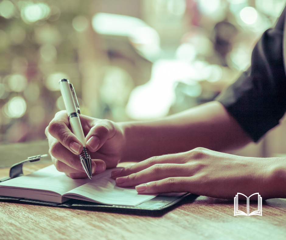 Hands of a women writing in a journal.