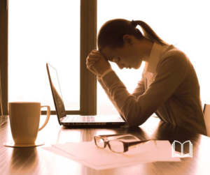 Women with her head on her hand, frustrated looking at her laptop.