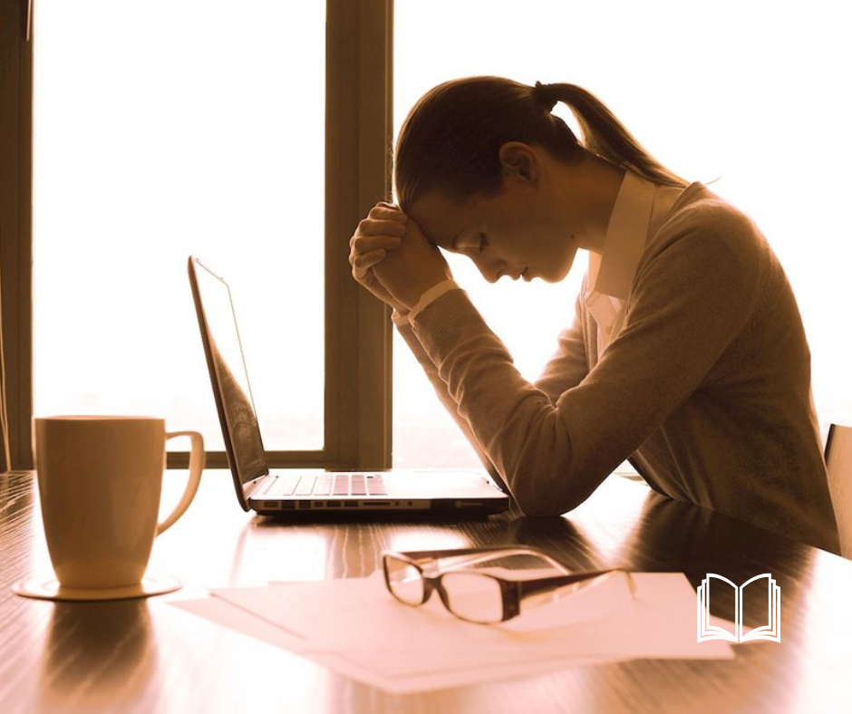 Women with her head on her hand, frustrated looking at her laptop.