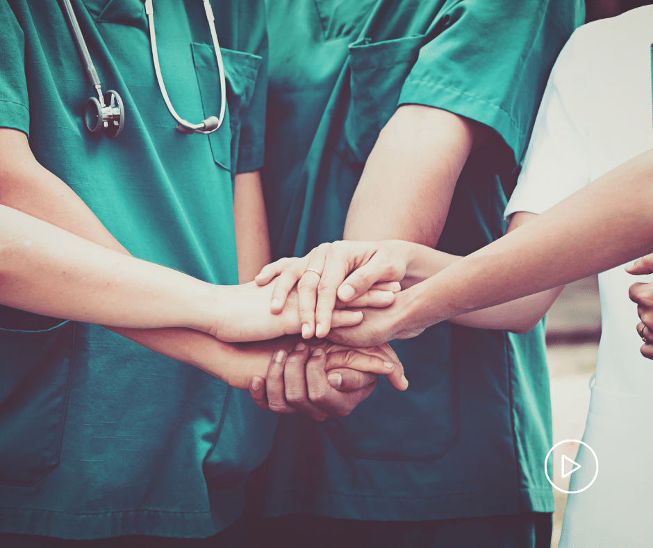 Medical Professionals wearing scrubs with their hands touching in a circle.