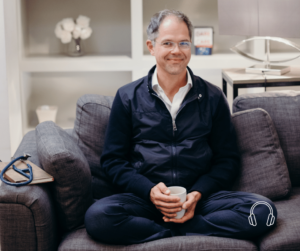 Prof Dr. Jan Bonhoeffer sitting with a glass of water on a gray couch.