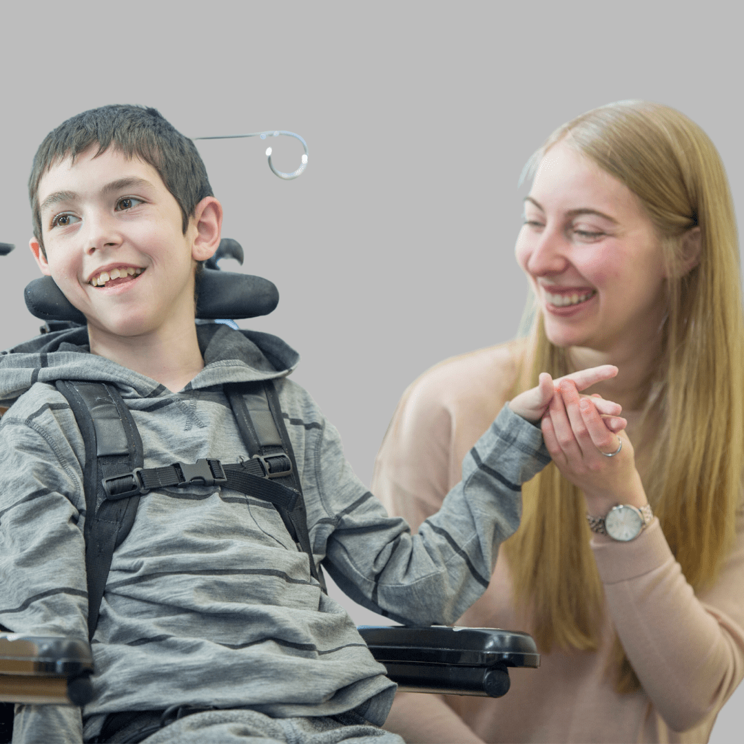 Carer holding the hands of a child in a wheelchair.